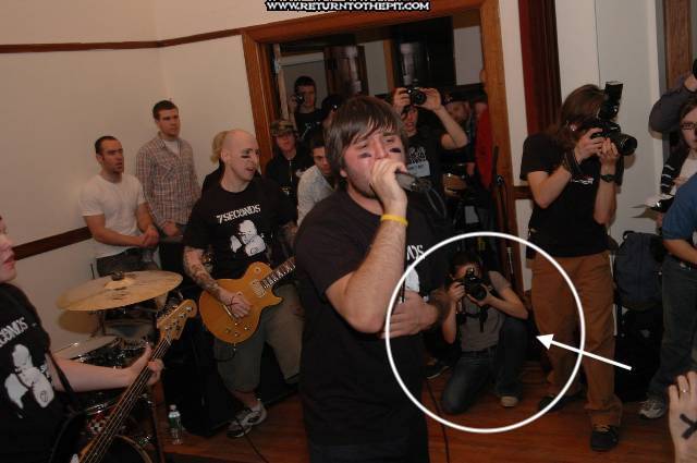 A band performs while someone is crouched low with an SLR camera.